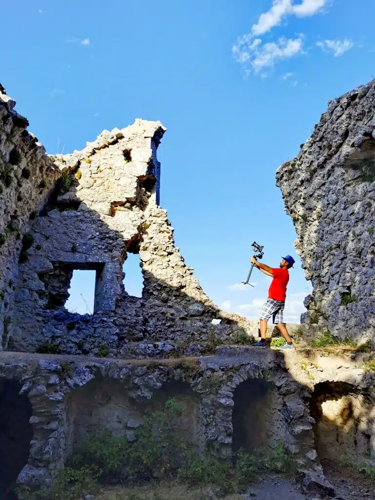 Filmmaker with gimbal capturing Monte Sacro ruins in Puglia, Italy.